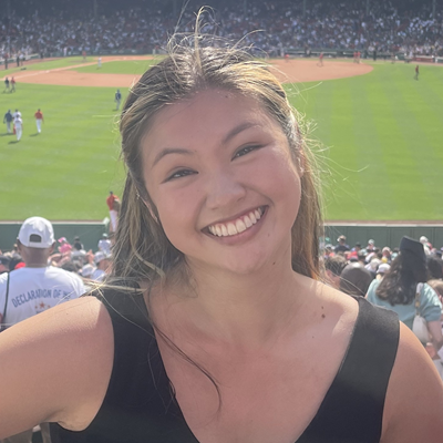 Headshot of Giannina Ong wearing a black top with a baseball field in the background.